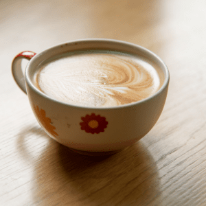 cup of coffee with flowers on it on table