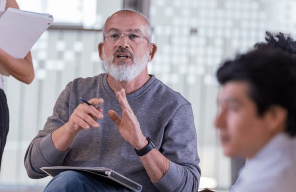 Man in glasses explaining to other team members 