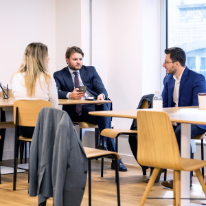 three colleagues collaborating on table wearing suits